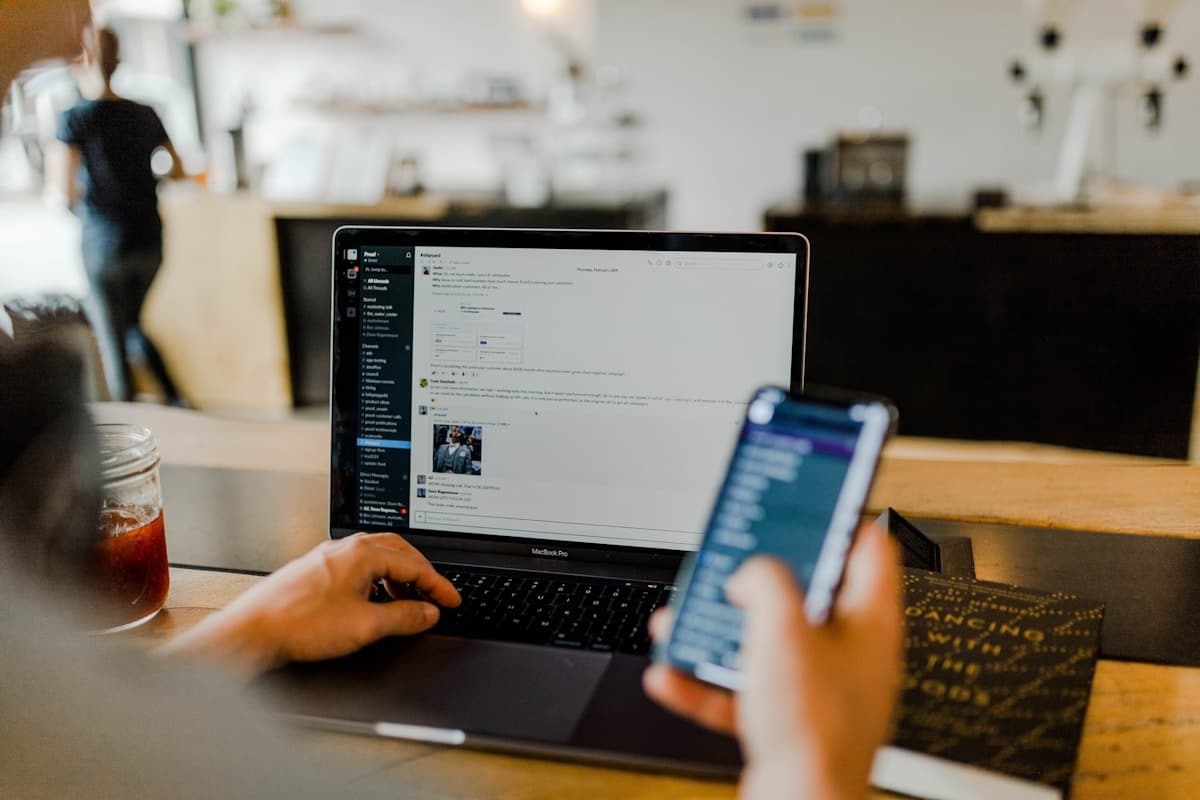 A professional working across a laptop and mobile device
